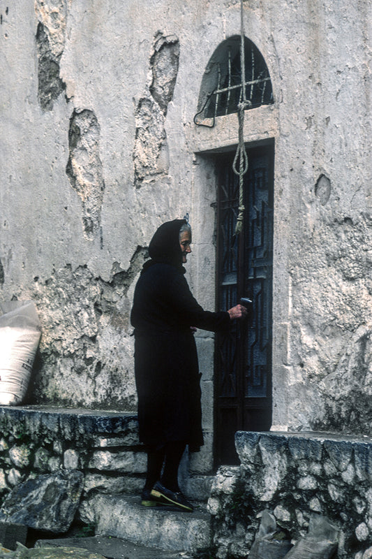 A woman from Mani opening the church door